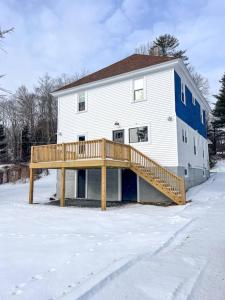 a house with a wooden deck in the snow at Kenoza House with Private Lake and Kayaks in Callicoon