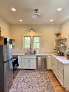 a kitchen with white cabinets and a stainless steel refrigerator at Kenoza House with Private Lake and Kayaks in Callicoon
