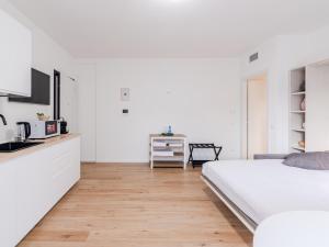 a white bedroom with a bed and a kitchen at GINO SUITES - Monolocali Luxury - Appartamenti vicini a Rho Fiera e Milano in Bollate