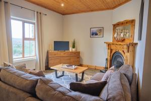 a living room with a couch and a fireplace at 5 Bedroom House By Travel Lets Holiday Homes Donegal With Sweeping Lake & Hill Views in Carrigart