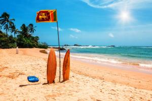 two surfboards and a flag in the sand on a beach at Blue Sky Villa Ahangama in Ahangama