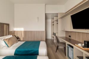 a hotel room with a bed and a desk with a television at Living Hotel Milano in Cornaredo
