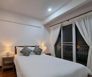 a bedroom with a white bed and a large window at The Lighthouse Seaview Hotel in Rawai Beach