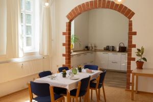 a dining room with a table and chairs and a kitchen at Herbergskirche Spangenberg - Stimmungsvolle Schlafräume, jedoch ist NUR das Badzimmer beheizt in Spangenberg