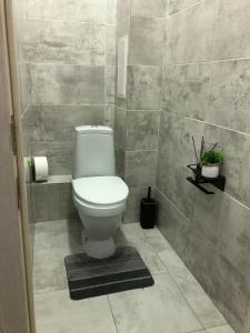 a bathroom with a toilet and a tiled wall at ЖК 'Арман ' in Aktobe