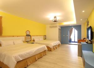 two beds in a hotel room with yellow walls at Sky Blue Ocean B&B in Eluan