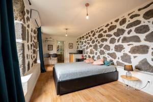 a bedroom with a stone wall and a bed at Liiiving in Açores - Casa de Foros in Foros