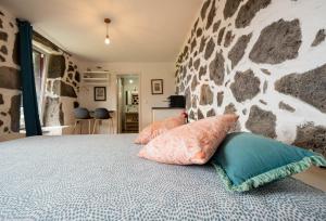 a bedroom with a stone wall and a bed with pillows at Liiiving in Açores - Casa de Foros in Foros