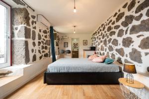 a bedroom with a stone wall and a bed with pillows at Liiiving in Açores - Casa de Foros in Foros