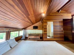 a bedroom with a wooden ceiling with a bed and a tv at Atobá Villas in Paraty