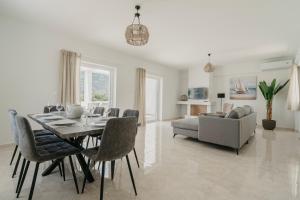 a dining room with a table and chairs and a couch at Areti White Villas in Loutraki