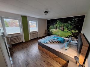 a bedroom with a large bed with a painting on the wall at FeWo Waldblick in Waxweiler +26 photos