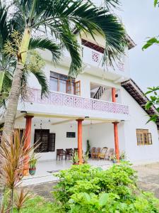 a house with a balcony and a palm tree at Moragalla Relax Stay in Beruwala