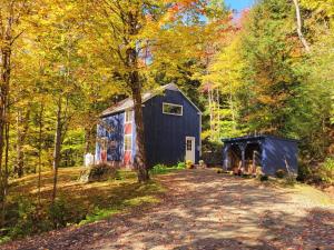 a blue barn in the middle of a forest at Morel Mountain Hideaway in Warren
