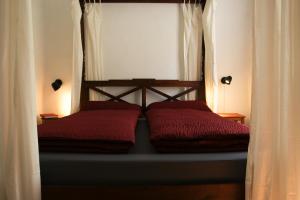 a bed with two red pillows in a bedroom at Herbergskirche Spangenberg - Stimmungsvolle Schlafräume, jedoch ist NUR das Badzimmer beheizt in Spangenberg +7 photos