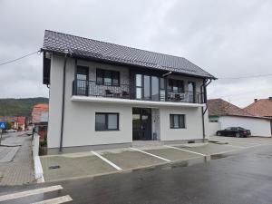 a white building with a balcony and a parking lot at Mini River in Sîngeorgiu de Pădure +8 photos