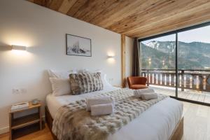 a bedroom with a large bed and a large window at Chalet Imperial by Altitudia in Morzine +20 photos