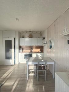 a kitchen with a white table and a dining room at FeWo GüNi Marina Wendtorf Strand mit Balkon und seitlichem Fördeblick in Wendtorf +19 photos
