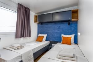 two beds in a room with a blue wall at Camp Panorama Plus with Pool in Drage