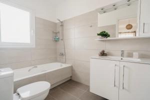 a white bathroom with a tub and a toilet and a sink at Areti White Villas in Loutraki