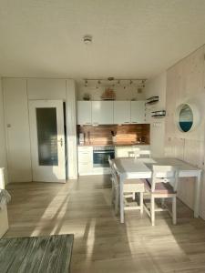 a kitchen with a white table and a table and chairs at FeWo GüNi Marina Wendtorf Strand mit Balkon und seitlichem Fördeblick in Wendtorf
