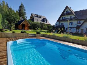 a swimming pool in front of a house at Pokoje u Teresy in Czarna Góra