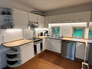 a kitchen with white cabinets and a wooden counter top at House direct to beach in Greve