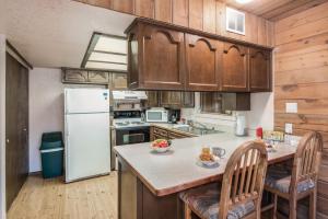 a kitchen with a white refrigerator and wooden cabinets at RockInn Pines in Ruidoso +18 photos
