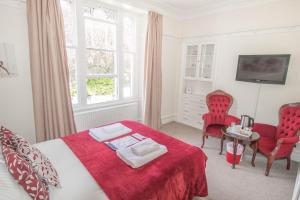 a bedroom with a bed and two red chairs at Elim Bank Guest House in Windermere