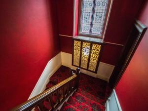 a staircase with a red wall and a window at Elim Bank Guest House in Windermere