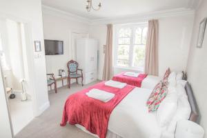 a white bedroom with two beds and a window at Elim Bank Guest House in Windermere