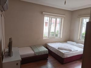 a bedroom with two beds and a desk and two windows at Dilara Hotel Pansiyon in Antalya