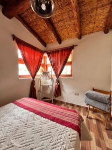 a bedroom with a bed with red curtains and a chair at Casa campo Ayllu in Tilcara +7 photos
