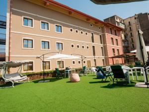 a large building with chairs and umbrellas on a lawn at ROOMS alCentro in Catania