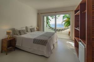 a bedroom with a bed and a view of the ocean at Pousada Natureza in Morro de São Paulo +273 photos