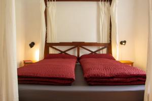 a bed with two red pillows on it with a window at Herbergskirche Spangenberg - Stimmungsvolle Schlafräume, jedoch ist NUR das Badzimmer beheizt in Spangenberg