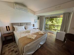 a bedroom with a large bed with two towels on it at Ilha de Toque Toque Eco Hotel in São Sebastião
