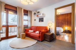 a living room with a red couch and a bedroom at Hostdomus - Clotes 33 in Sauze d'Oulx