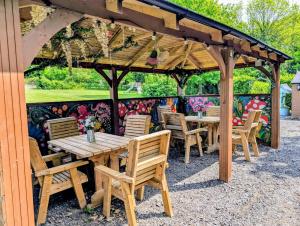 a wooden table and chairs under a wooden pergola at Kits Coty Glamping in Maidstone