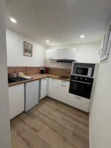 a kitchen with white cabinets and a stove top oven at Charmant appartement moderne D in La Roche-sur-Yon