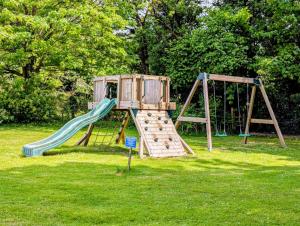 a wooden playground with a slide in the grass at Kits Coty Glamping in Maidstone