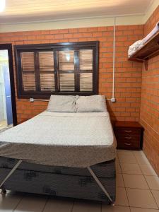 a bedroom with a bed in a brick wall at Casa praia bella torres in Passo De Torres