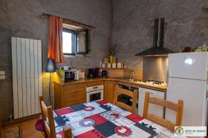 a kitchen with a table and a white refrigerator at Le Gîte de Saint Izaire in Saint-Izaire +21 photos