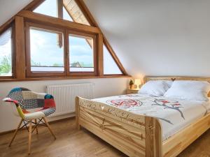 a bedroom with a bed and a chair and windows at Willa Mnich in Zakopane