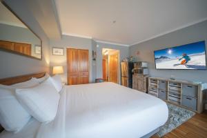 a bedroom with a large white bed and a flat screen tv at Gateway Lodge 5084 by SummitCove Lodging in Colorado in Keystone