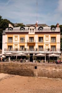 a large yellow building on the beach next to the water at Hôtel De La Vallée in Dinard