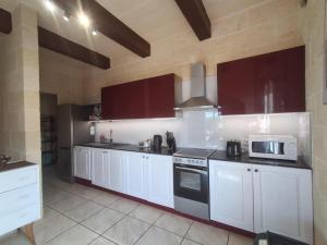 a kitchen with white cabinets and a microwave at Sunsets Farmhouse, Nadur Gozo in Nadur