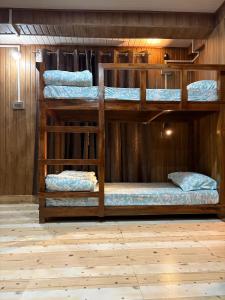 three bunk beds in a room with a wooden wall at Bunk Stays in Darjeeling