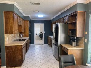a kitchen with wooden cabinets and a stainless steel refrigerator at 4-Bedroom Home with Private Pool in Euless in Euless