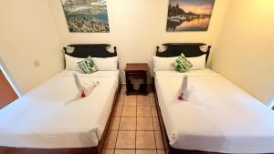 two beds in a room with white sheets at Mayan Princess Beach & Dive Resort in West Bay